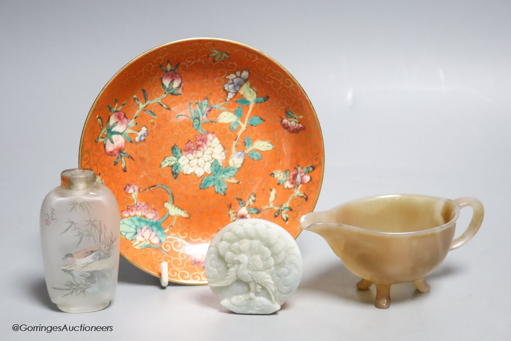 A Chinese jadeite roundel, an agate sauceboat, an inside painted snuff bottle and a ceramic charger, Qing period or later, diameter 14cm